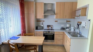 A compact kitchen with wooden cabinets, a built-in oven, a coffee maker, and a small refrigerator. - Sonnenhof Holiday Apartment 4 (Enkirch)