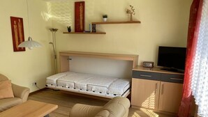 A compact living space with a sofa, a small table, a bed with a mattress, a TV, and a cabinet. - Sonnenhof Holiday Apartment 4 (Enkirch)