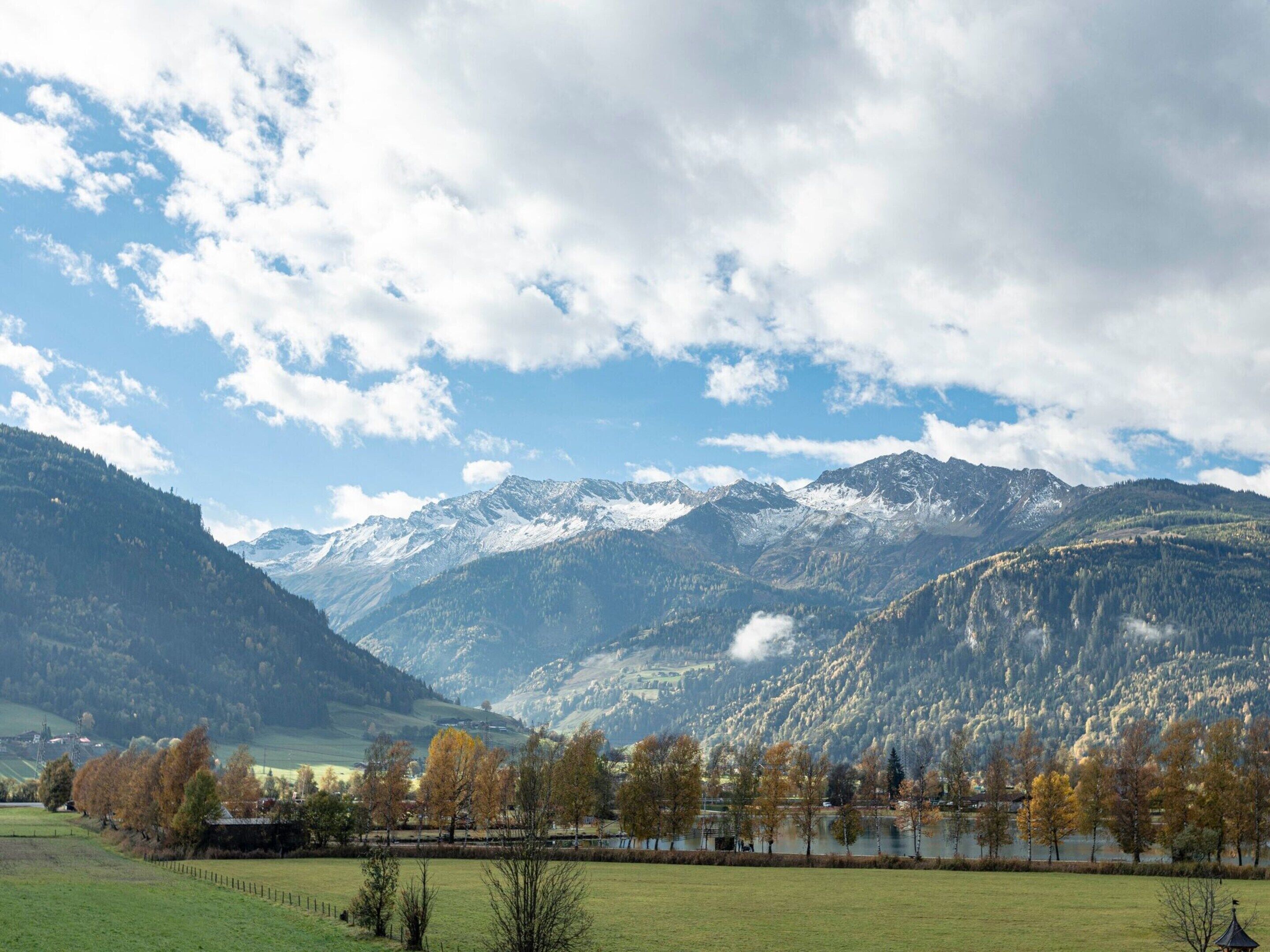 A mountainous landscape with a lake, trees, and a clear sky.