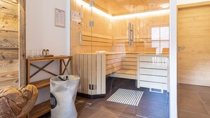 A sauna room with wooden walls and a glass door, a wooden bench, a towel rack, and a trash bin. - Luxury Chalet With Private Sauna in Uttendorf (Uttendorf)