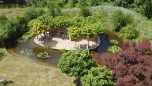 An outdoor area with a circular seating arrangement surrounded by trees and a pond. - 12 Bohler Brise Modern Retreat (St. Peter-Ording)