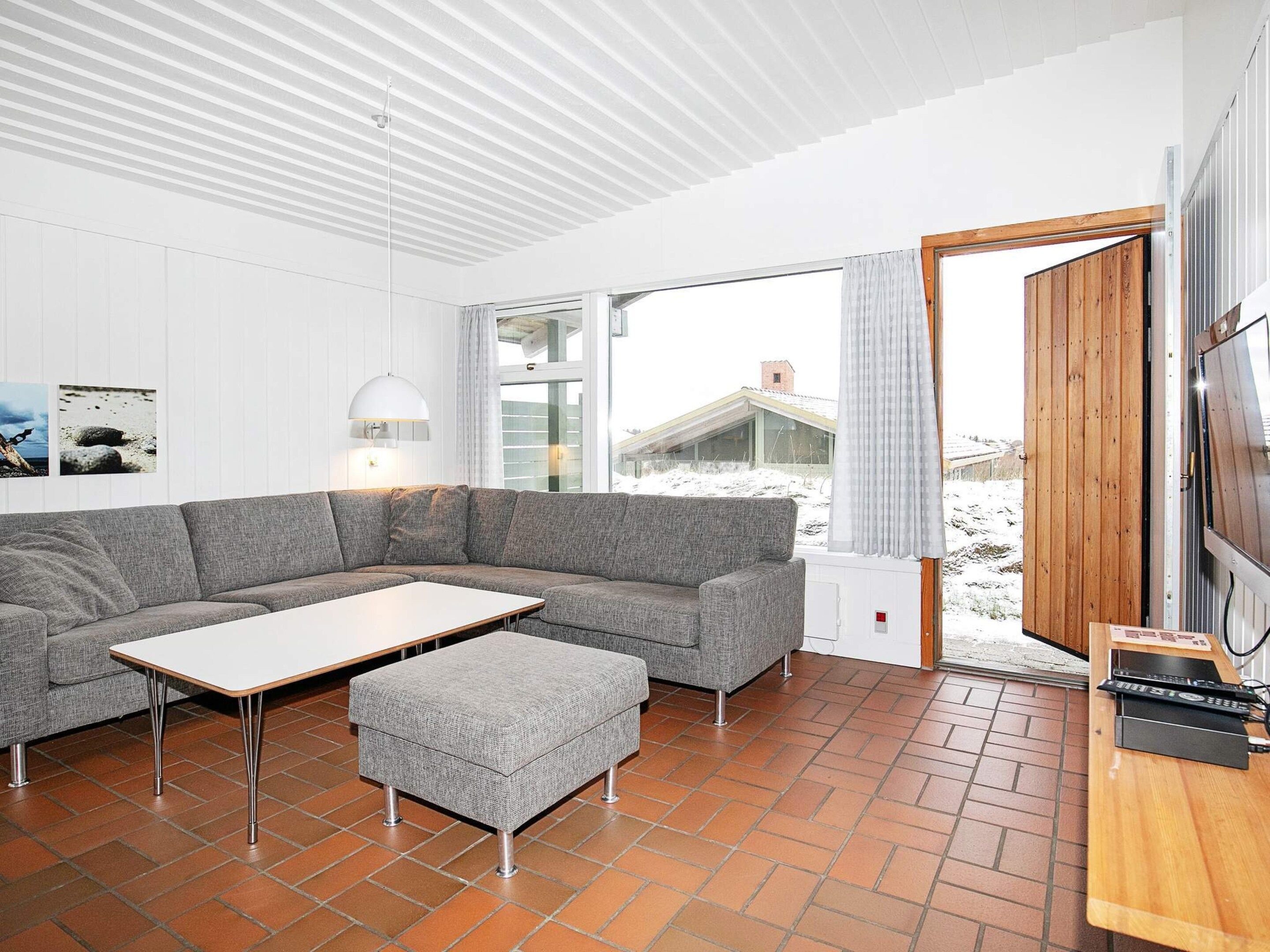 A modern living room with a grey sectional sofa, a small table, and a wooden TV stand.