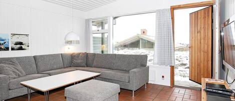A modern living room with a grey sectional sofa, a small table, and a wooden TV stand.
