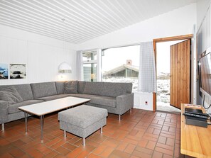 Uma sala de estar moderna com um sofá seccional cinza, uma mesinha e um aparador de madeira.