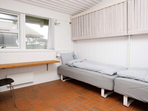 Una habitación pequeña y acogedora con una cama individual, un banco de madera y una ventana.