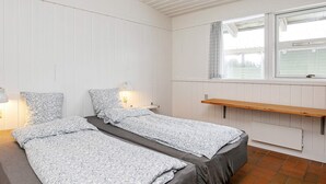 A bedroom with two beds, a window, a shelf, and a lamp. - 6 Person Holiday Park Home in Hanstholm (Hanstholm)