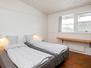 Un dormitorio con dos camas, una ventana, un estante y una lámpara.