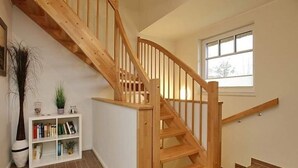 A wooden staircase with a white wall and a window on the landing. - Rieten Huis "oostzeegolf" (Boltenhagen)