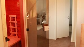 A hallway with a wooden bench, a staircase, and a door leading to a bedroom. - Rieten Huis "oostzeegolf" (Boltenhagen)