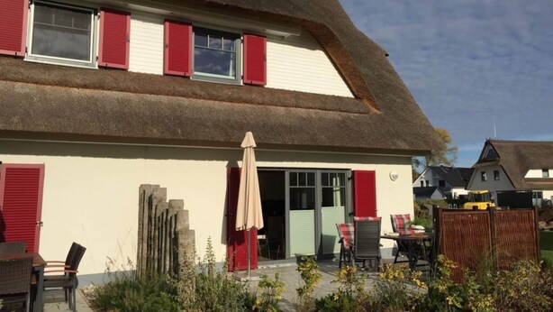 A traditional building with a steeply pitched thatched roof and red shutters. - Rieten Huis "oostzeegolf" (Boltenhagen)