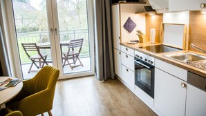 Une cuisine moderne avec une porte-fenêtre coulissante donnant sur un balcon, une table à manger et une chaise jaune.