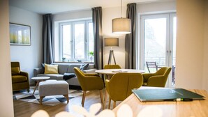 Un salon moderne avec un canapé, des fauteuils, une table ronde et une lampe.