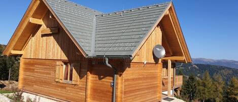 Una cabaña de madera con techo inclinado, un pequeño porche y vistas del paisaje circundante.