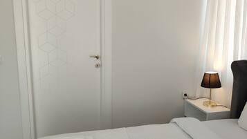 Habitación de hotel con cama, mesita de noche con lámpara, equipo de aire acondicionado y puerta con diseño geométrico.