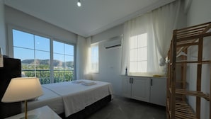A hotel room with a bed, a bedside table with a lamp, a wardrobe, and a window with a view of the outdoors. - The Dalaman Suites & Pension Dalaman Airport 10 km (Dalaman)