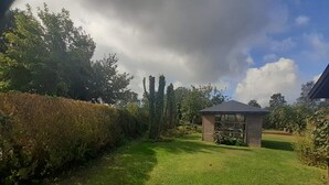 A garden with a gazebo, a hedge, and trees. - 6 Person Holiday Home in Rodvig Stevns (Rodvig Stevns)