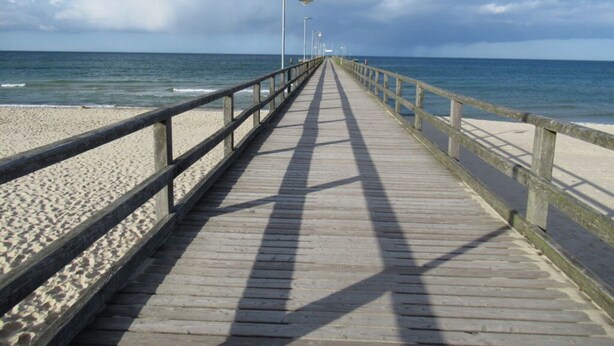 A wooden pier extending into a beach with a clear sky. - In the Villa Granitz (Göhren)