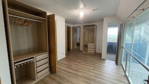Ein geräumiges Zimmer mit großem Kleiderschrank, begehbarem Kleiderschrank und einem Balkon mit Glasgeländer.