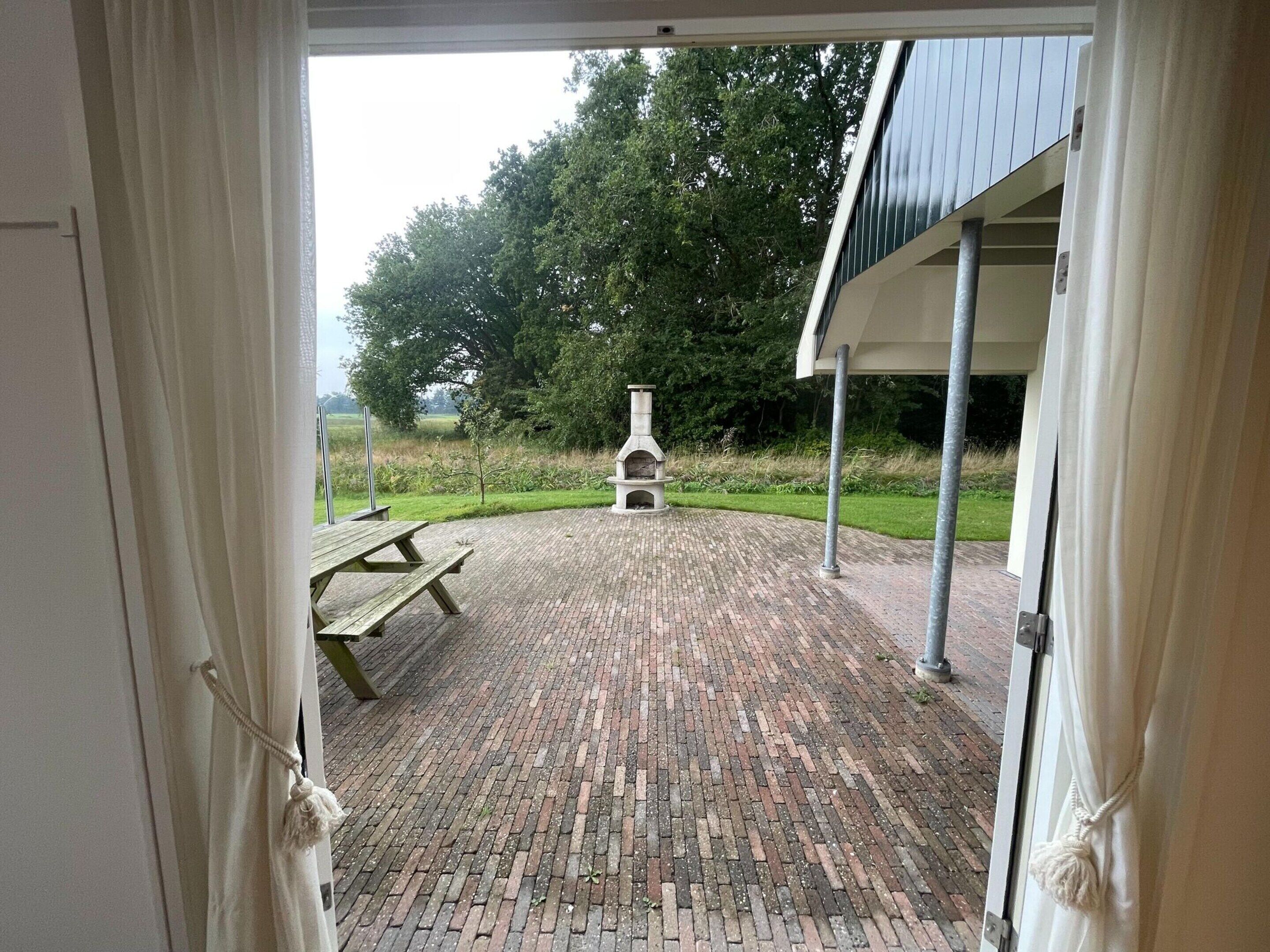 An outdoor patio with a brick floor, a stone barbecue, and a picnic table.
