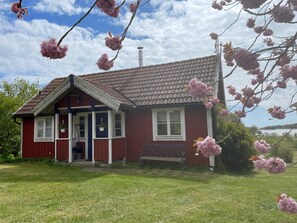 Un bâtiment rouge avec un toit en tuiles, un porche et un banc.