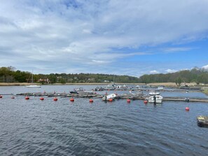 A marina with boats docked and red buoys in the water.