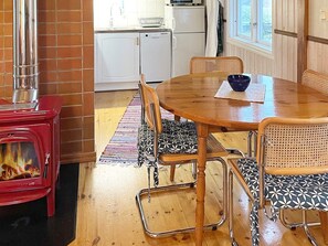 A cozy kitchen with a red stove, white cabinets, and a dining area with a wooden table and chairs.