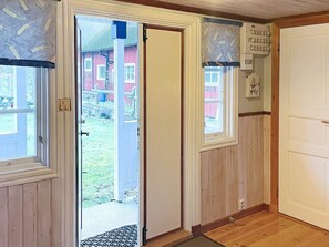 A room with a wooden floor, a door leading outside, and a window with a view of a red building. - 4 Star Holiday Home in Ronneby (Ronneby)