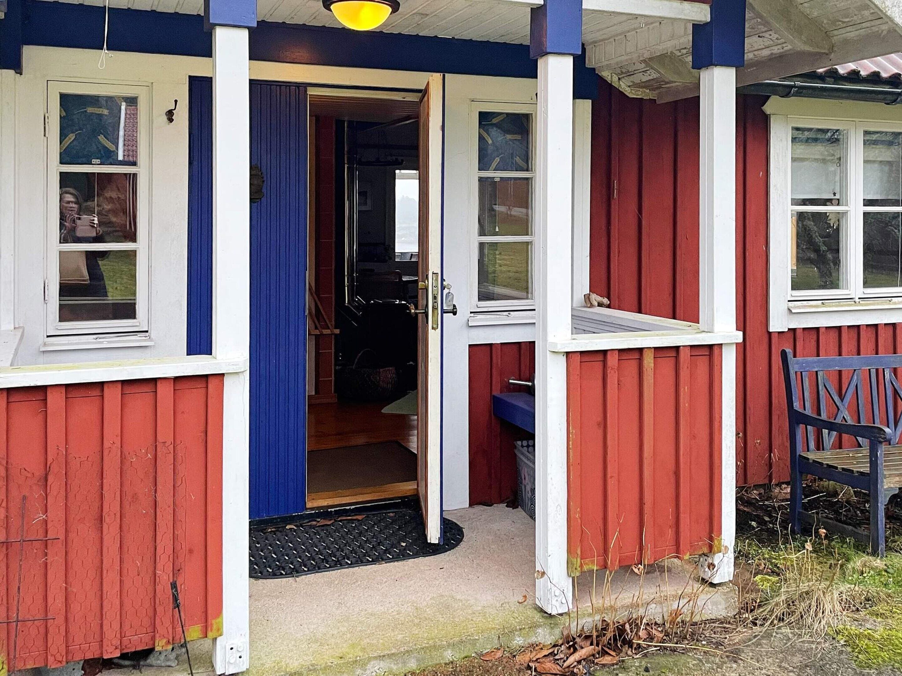 A red and white building with a porch, a door, and a bench.