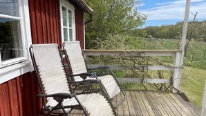 Een houten terras met twee loungestoelen en een bijzettafeltje.