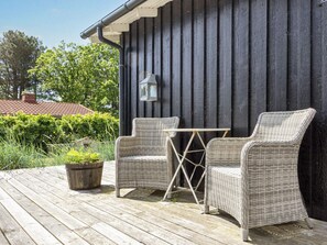 A wooden deck with wicker furniture and a lantern. - 4 Star Holiday Home in Hadsund (Hadsund)