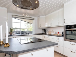 A modern kitchen with white cabinets, a granite countertop, and a built-in oven. - 4 Star Holiday Home in Hadsund (Hadsund)