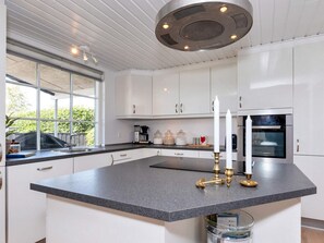 A modern kitchen with white cabinets, a granite countertop, and a built-in oven.