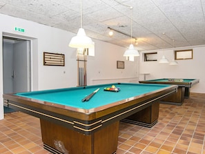 Enjoy a game of pool in this well-lit room with two tables and framed artwork on the walls.