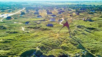 Un paysage rural parsemé de maisons et dominé par une structure rouge en forme d’étoile.