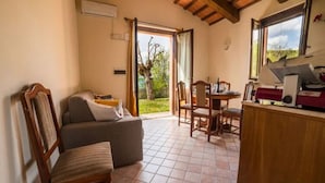 A cozy living area with a sofa, chairs, a dining table, and a kitchen area with a counter and appliances. - Holiday Home in Urbania With Garden BBQ (Urbania)