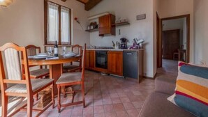 A cozy dining area with a wooden table and chairs, a kitchen with wooden cabinets, and a tiled floor. - Holiday Home in Urbania With Garden BBQ (Urbania)