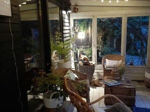 A cozy indoor space with a wicker chair, a wooden table, and various plants.