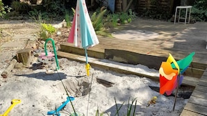 Et sandlegeområde med en skovl, en spand og en vindmølle.