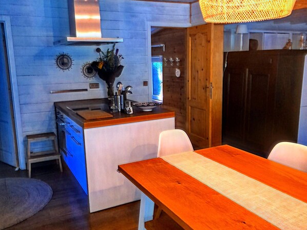 A compact kitchen with a wooden island, white cabinets, and a dining table with chairs.
