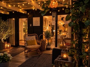 A cozy interior with a wicker chair, a dining area, and string lights. - Charming Forest House on the Purple Heath (Arendonk)