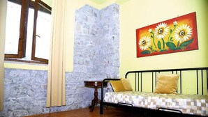 A room with a stone wall, a bed with a checkered mattress, a small table, and a painting of daisies. - Holiday Home in Trivigno With Pool and Garden (Trivigno)