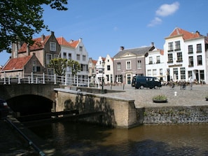 A historic town square with a bridge over a canal, surrounded by traditional European buildings. - Huijsmans Verhuur Type B de Luxe Haringvliet 4 (Ouddorp)