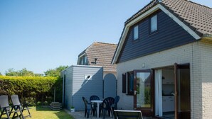 Une maison dotée d’un patio, d’une petite table et de chaises d’extérieur.