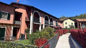 A row of Mediterranean-style buildings with arched balconies and a central walkway. - Perlago Comfortable Holiday Residence (Costermano sul Garda)