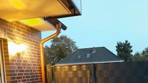 A brick building with a gated entrance and a paved patio area. - Holiday Apartment Cabin 2c (Norden)