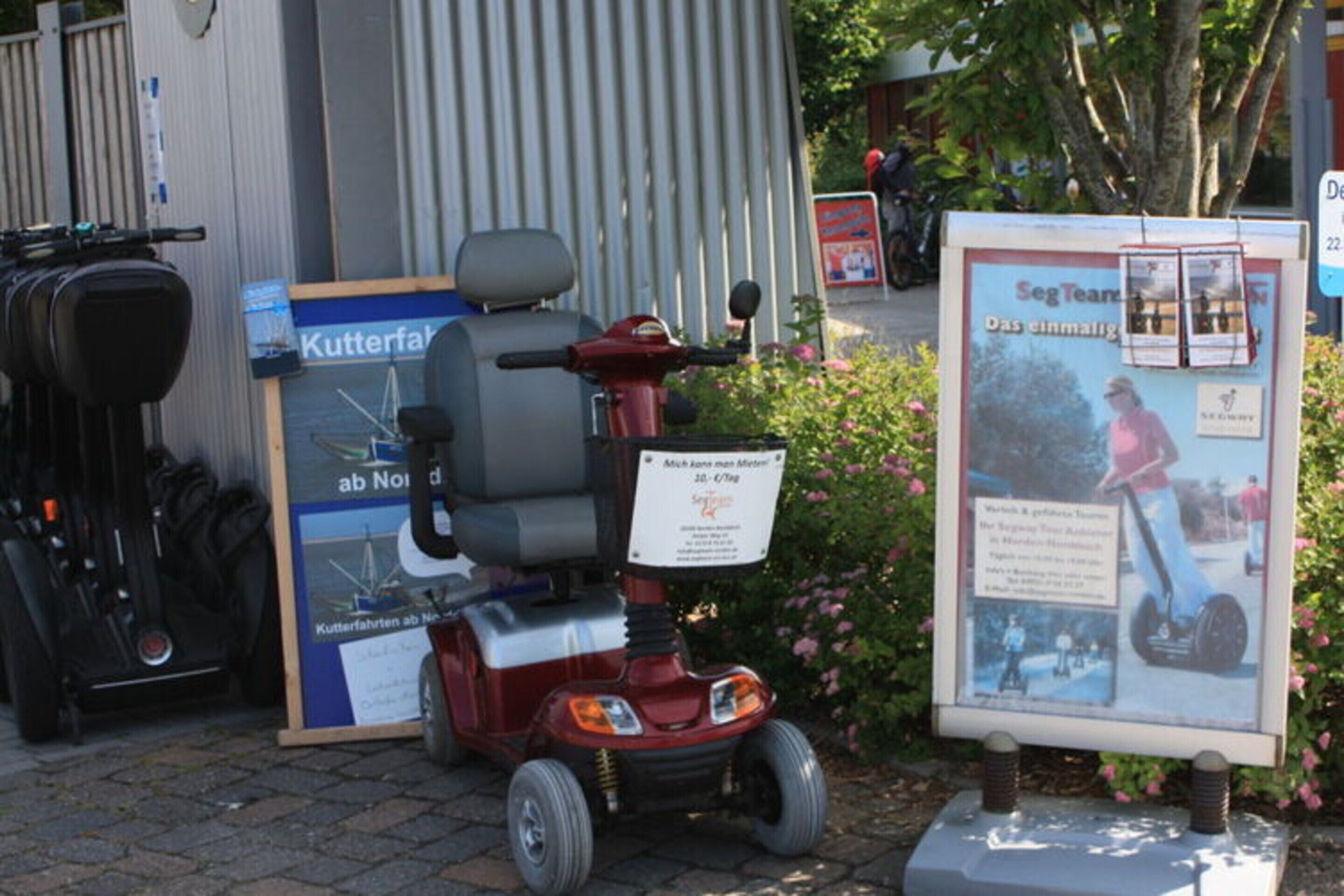 A mobility scooter parked in front of a building with a signboard and a sign indicating a nearby location.