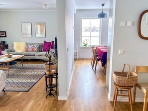A spacious living room with a sofa, coffee table, and a dining area with a table and chairs. There are framed pictures on the wall and a window providing natural light. - 5 Star Holiday Home in Lottorp (Löttorp)