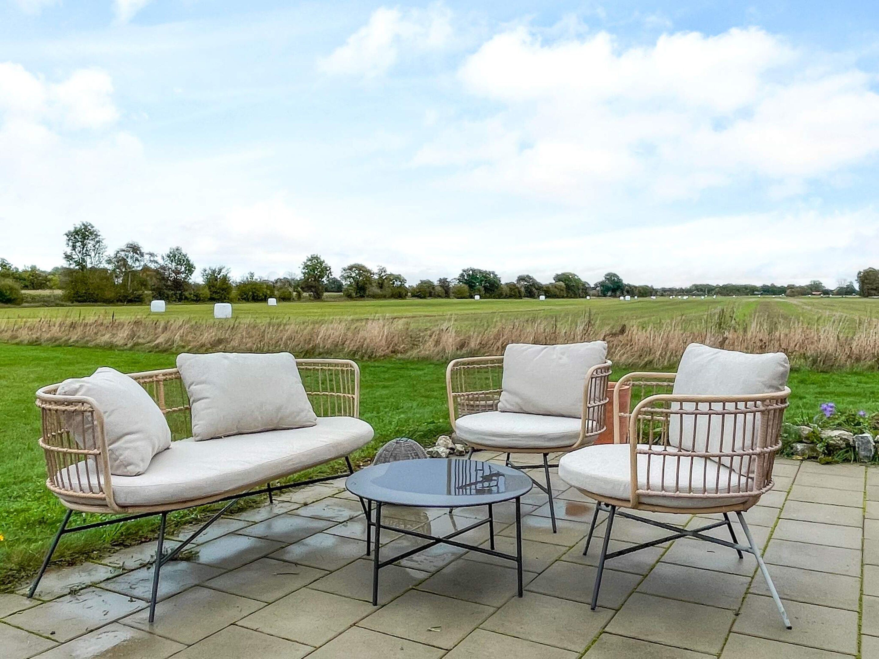 A patio with wicker furniture and a glass table.