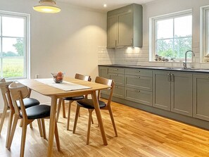 A modern kitchen with a wooden dining table, chairs, and grey cabinets. - 5 Star Holiday Home in Lottorp (Löttorp)