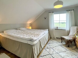 A bedroom with a bed, a chair, a window with curtains, and a lamp. - 5 Star Holiday Home in Lottorp (Löttorp)